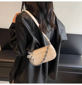 Detail of beige checkered baguette bag with metal chain and rabbit charm on model