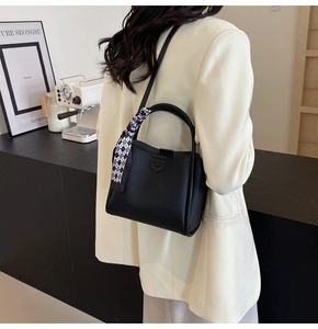 Litchi pattern black bucket bag with houndstooth scarf detail on model in white blazer