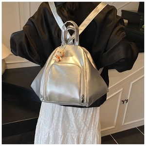 Detail view of silver metallic triangular backpack with orange headphone mascot charm