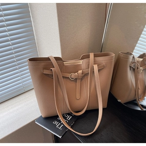 Macro detail of brown lychee grain leather tote bag with buckle strap and stitching