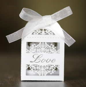 White laser-cut Love candy box with intricate floral patterns and a white organza ribbon bow