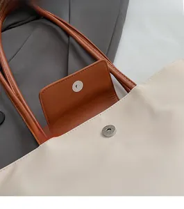 Detail of the magnetic closure on a beige tote bag with brown leather accents