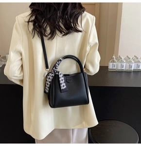 Detail of black lychee grain leather bucket bag with checkered silk scarf on handle