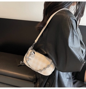 Detail of beige checkered baguette bag with silver chain and cute balloon dog charm
