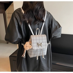 Détail du mini sac à dos à carreaux avec boucle papillon et breloque ours en peluche
