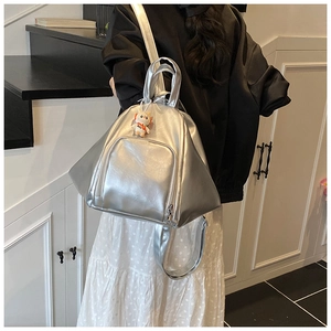 Silver geometric backpack with metallic mirror finish and a small cat charm accessory