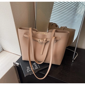 Detail of camel leather tote bag with lychee texture and gold buckle on a wooden desk