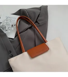 Detail of beige oxford tote bag with brown leather straps and embossed CLEAROK logo