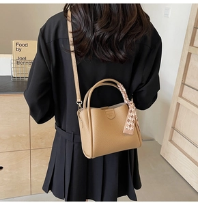 Detail of camel lychee grain leather tote bag with silk scarf on a black dress