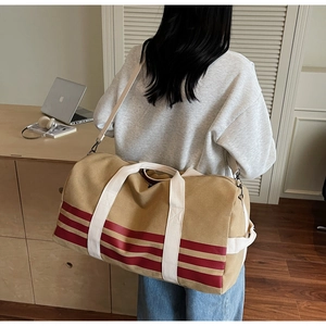 Rear view of khaki canvas travel bag with red stripes carried by a model in a studio