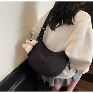Model view of black nylon dumpling bag with adjustable strap and cute bear charm