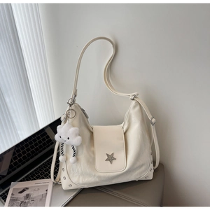 Close-up of cream leather shoulder bag with star buckle, rivets and cloud charm