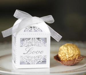 Macro view of white laser-cut LOVE candy box with ribbon and gold chocolate