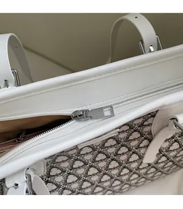 Detail view of the silver metal zipper and smooth geometric pattern on white tote bag