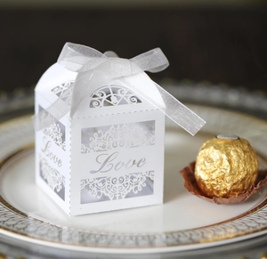 Close-up of white laser-cut wedding favor box with LOVE text and elegant ribbon bow