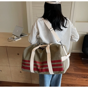 Close-up of olive canvas travel bag with red stripes and reinforced handles