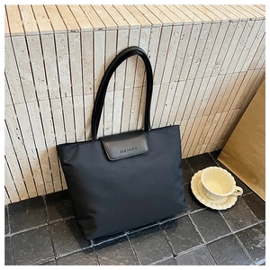 Detail shot of black waterproof nylon tote bag with embossed OLEAKUK flap on stone background