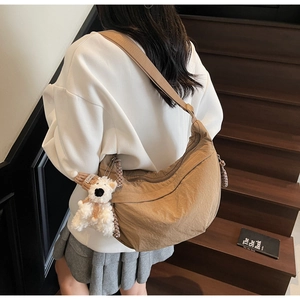 Detail of coffee brown nylon dumpling bag with cute plush bear pendant on model