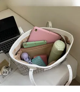 Top-down view of a spacious tote bag interior holding a tablet, bottle, and daily items