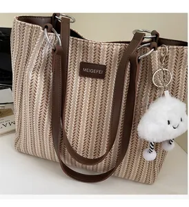 Detail of striped canvas tote bag featuring leather handles and plush cloud charm