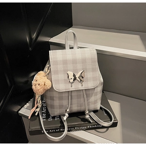 Détail du sac à dos à carreaux gris avec fermoir papillon et breloque ours en peluche