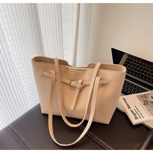 Detail of beige lychee grain leather tote bag showing decorative buckle and dual straps