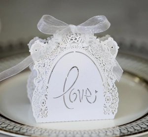Detailed laser-cut white wedding favor box with LOVE lettering and a white ribbon