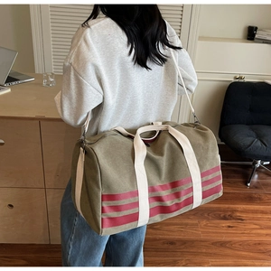Detailed back view of an olive green travel bag with red stripes on a model