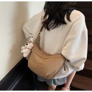 Back view of brown crescent dumpling bag with plush bear charm on a model