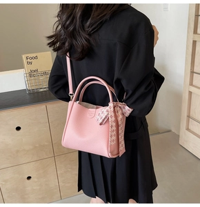 Detail of pink lychee leather handbag featuring decorative plaid scarf and shoulder strap