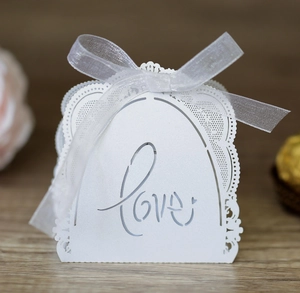 Detail of white laser-cut lace candy box with Love lettering and white organza ribbon bow