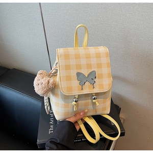 Détail d'un mini sac à dos à carreaux jaunes avec papillon argenté et breloque ours