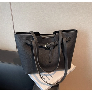 Close-up of black litchi texture leather tote bag with silver buckle and dual straps