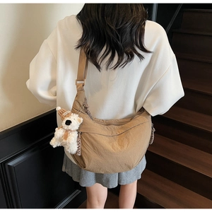 Brown nylon crescent bag with adjustable wide strap and white bear plush charm on side