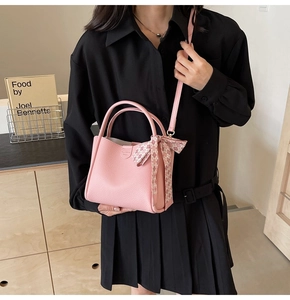 Close-up of pink pebbled leather bucket bag with silk scarf on a black shirt