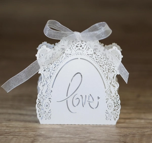 Close-up of white laser-cut wedding favor box with Love text and floral patterns