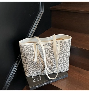 Close-up of geometric pattern tote bag on wooden stairs with book props