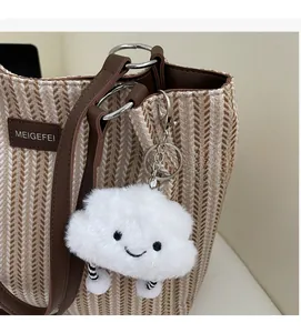 Close-up of a white plush cloud charm with embroidery on a woven striped canvas tote bag
