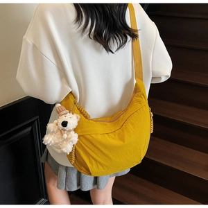 Detail of yellow nylon dumpling bag featuring a cute plush bear pendant on the strap