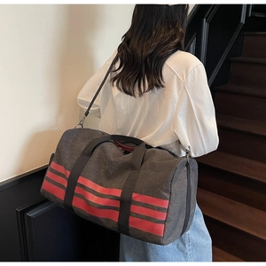 Detailed view of charcoal canvas travel bag with three red stripes and black shoulder strap