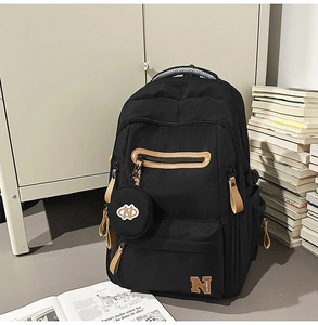 Close-up of black canvas backpack featuring vintage leather zipper pull and small coin pouch