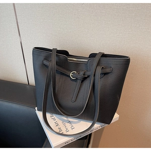 Macro detail of black lychee grain leather tote bag featuring gold buckle decoration