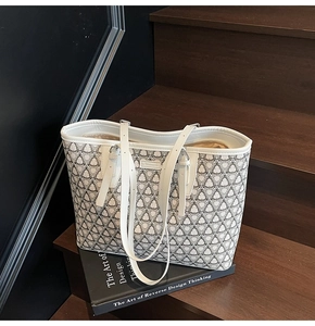 Detail of white tote bag with black geometric patterns on a wooden staircase