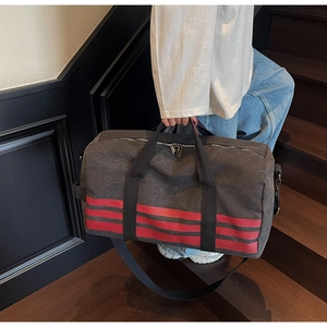 Detail of grey canvas travel duffel bag with red stripes and durable carry handles