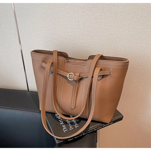 Detail of caramel brown tote bag with white contrast stitching and decorative buckle