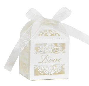 Detailed view of white pearlescent wedding favor box with laser-cut hollow pattern and silk ribbon