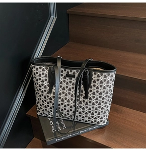 Detail of checkered tote bag with leather straps resting on a wooden staircase