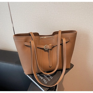 Detail showing brown lychee textured leather tote bag with white contrast stitching