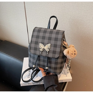 Détail d'un mini sac à dos à carreaux gris avec boucle papillon argentée et charm ours doux