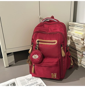 Close-up of burgundy high-density nylon backpack with leather pulls and small round pouch